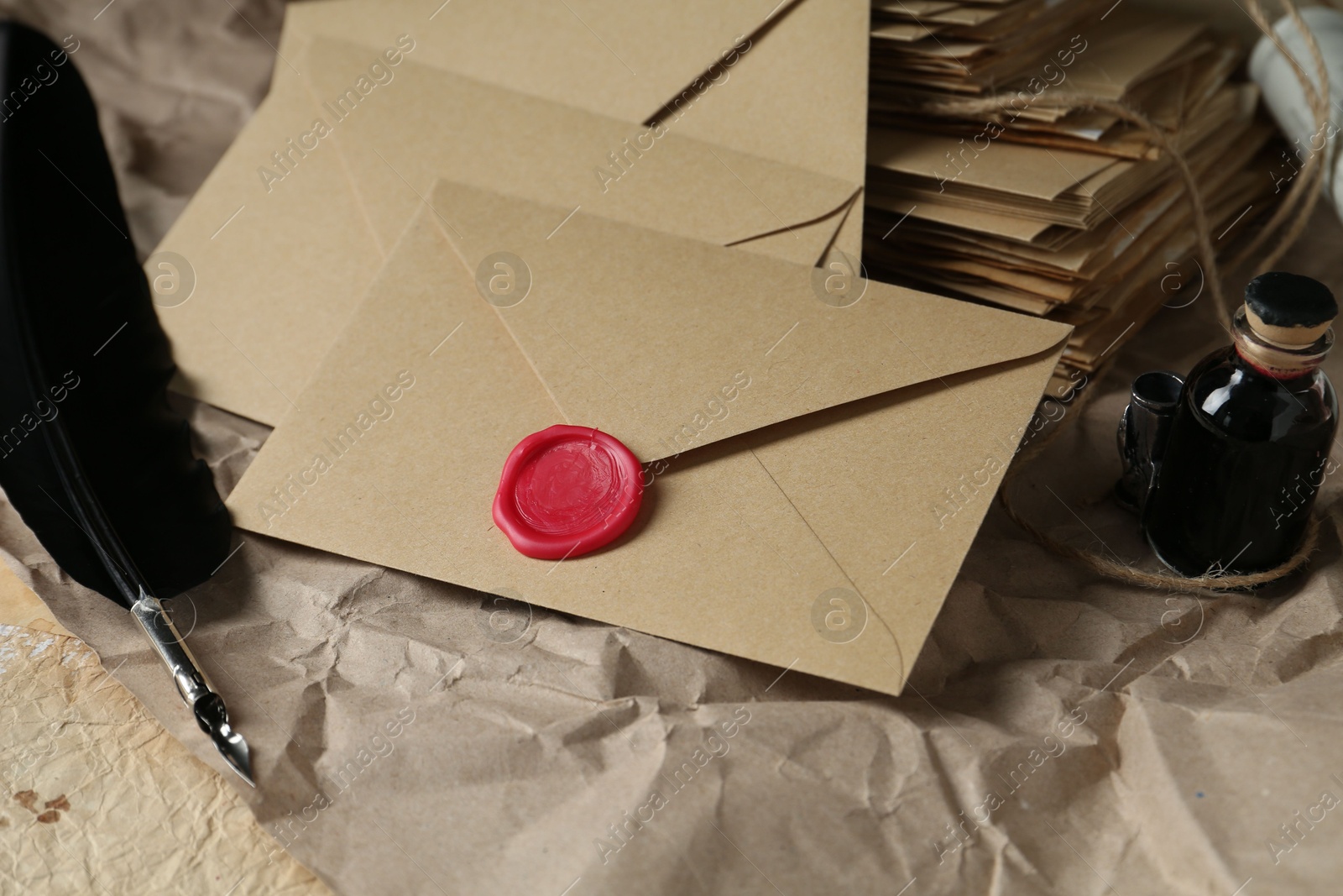 Photo of Stack of love letters, quill and ink on table, closeup