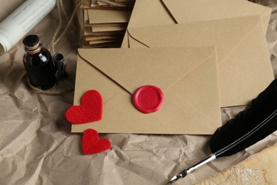 Photo of Stack of love letters, paper hearts, quill and ink on table, closeup