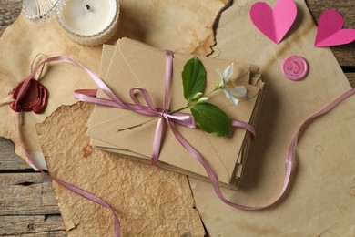 Photo of Stack of love letters, flower, paper hearts, candle and parchment sheets on wooden table, flat lay