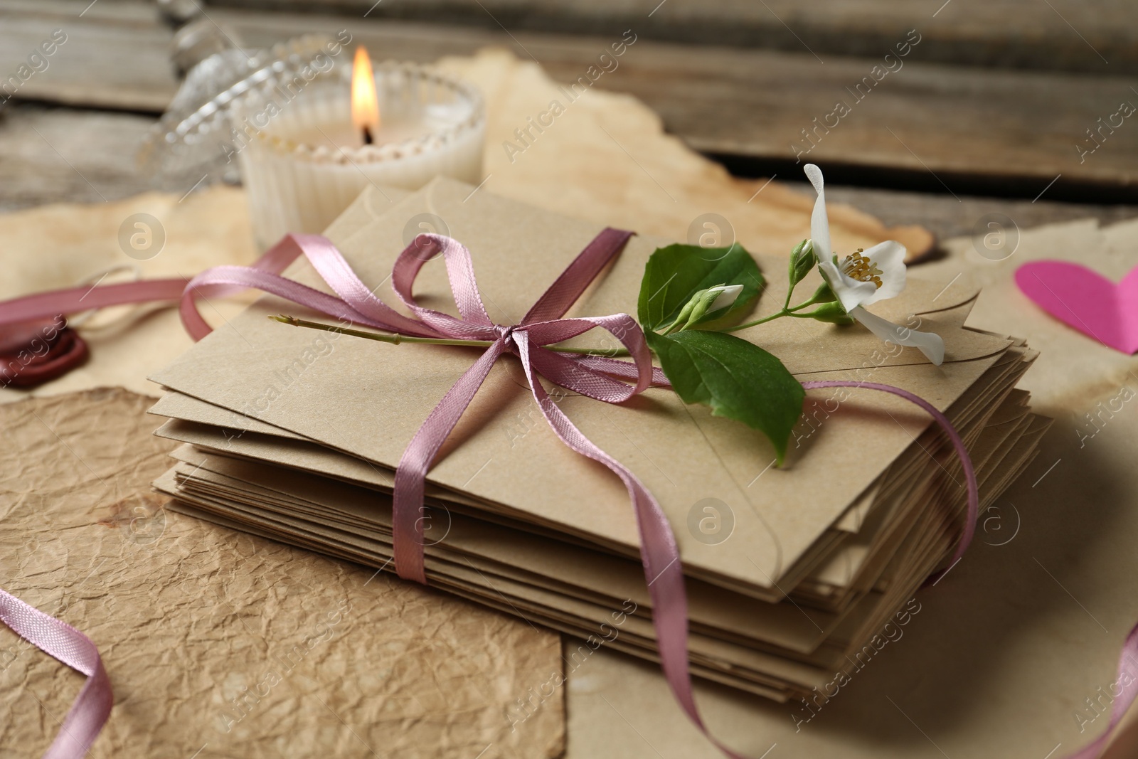Stack of love letters, flower, candle and parchment sheets on wooden table, closeup Photo of Stack of love letters, flower, candle and parchment sheets on wooden table, closeup