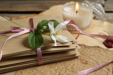 Photo of Stack of love letters, flower, candle and parchment sheets on wooden table, closeup