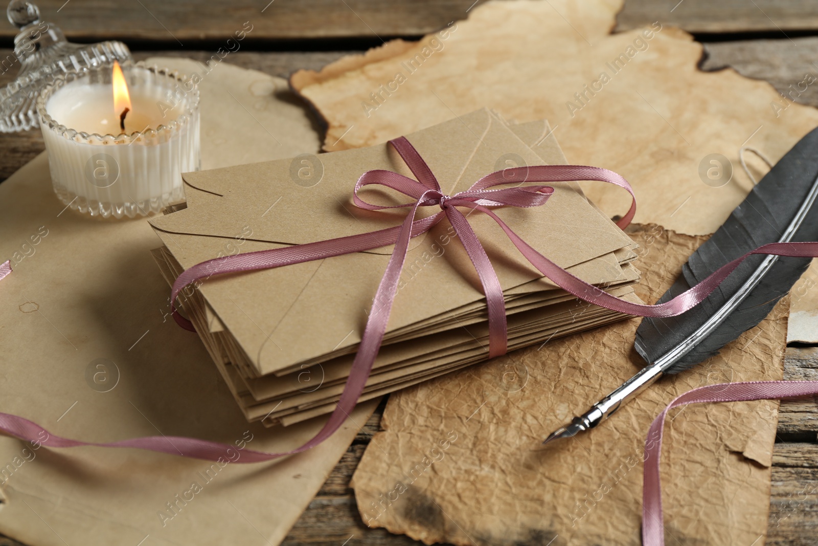 Stack of love letters, quill and parchment sheets on wooden table, closeup Photo of Stack of love letters, quill and parchment sheets on wooden table, closeup