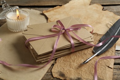 Photo of Stack of love letters, quill and parchment sheets on wooden table, closeup