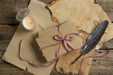 Photo of Stack of love letters, quill and parchment sheets on wooden table, flat lay