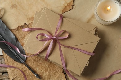 Photo of Stack of love letters, quill and parchment sheets on wooden table, flat lay