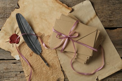 Photo of Stack of love letters, quill and parchment sheets on wooden table, flat lay