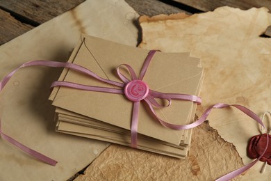 Photo of Stack of love letters and parchment sheets on wooden table, closeup