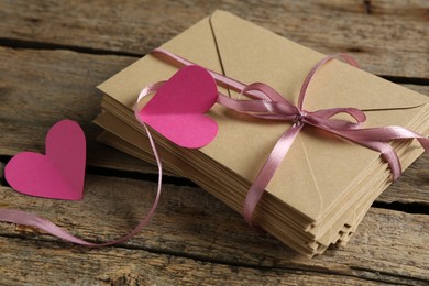 Photo of Stack of love letters and paper hearts on wooden table, closeup
