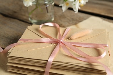 Photo of Stack of love letters and parchment sheet on wooden table, closeup