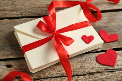 Photo of Stack of love letters and paper hearts on wooden table, closeup