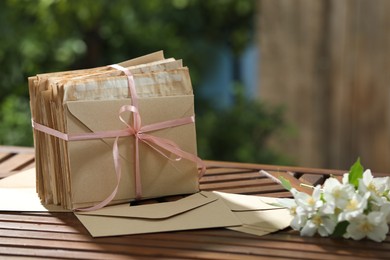 Photo of Stack of love letters and flowers on wooden table. Space for text