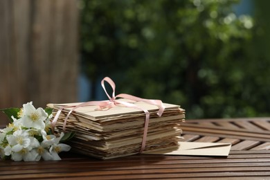 Photo of Stack of love letters and flowers on wooden table. Space for text