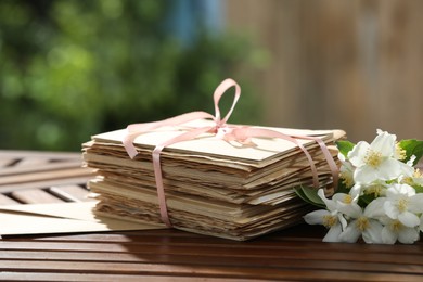 Photo of Stack of love letters and flowers on wooden table. Space for text