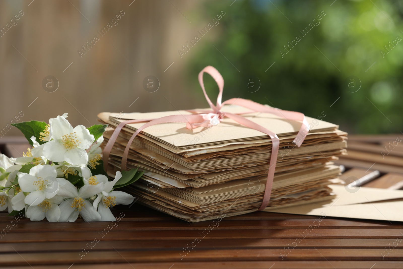 Photo of Stack of love letters and flowers on wooden table