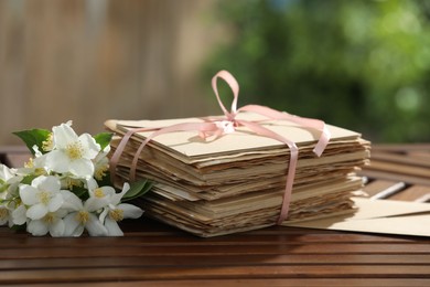 Photo of Stack of love letters and flowers on wooden table