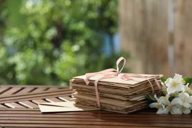 Photo of Stack of love letters and flowers on wooden table. Space for text