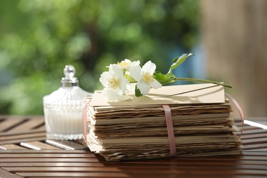 Photo of Stack of love letters and flowers on wooden table, closeup. Space for text