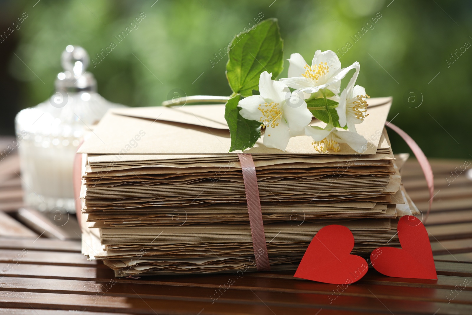 Stack of love letters, paper hearts and flowers on wooden table, closeup Photo of Stack of love letters, paper hearts and flowers on wooden table, closeup