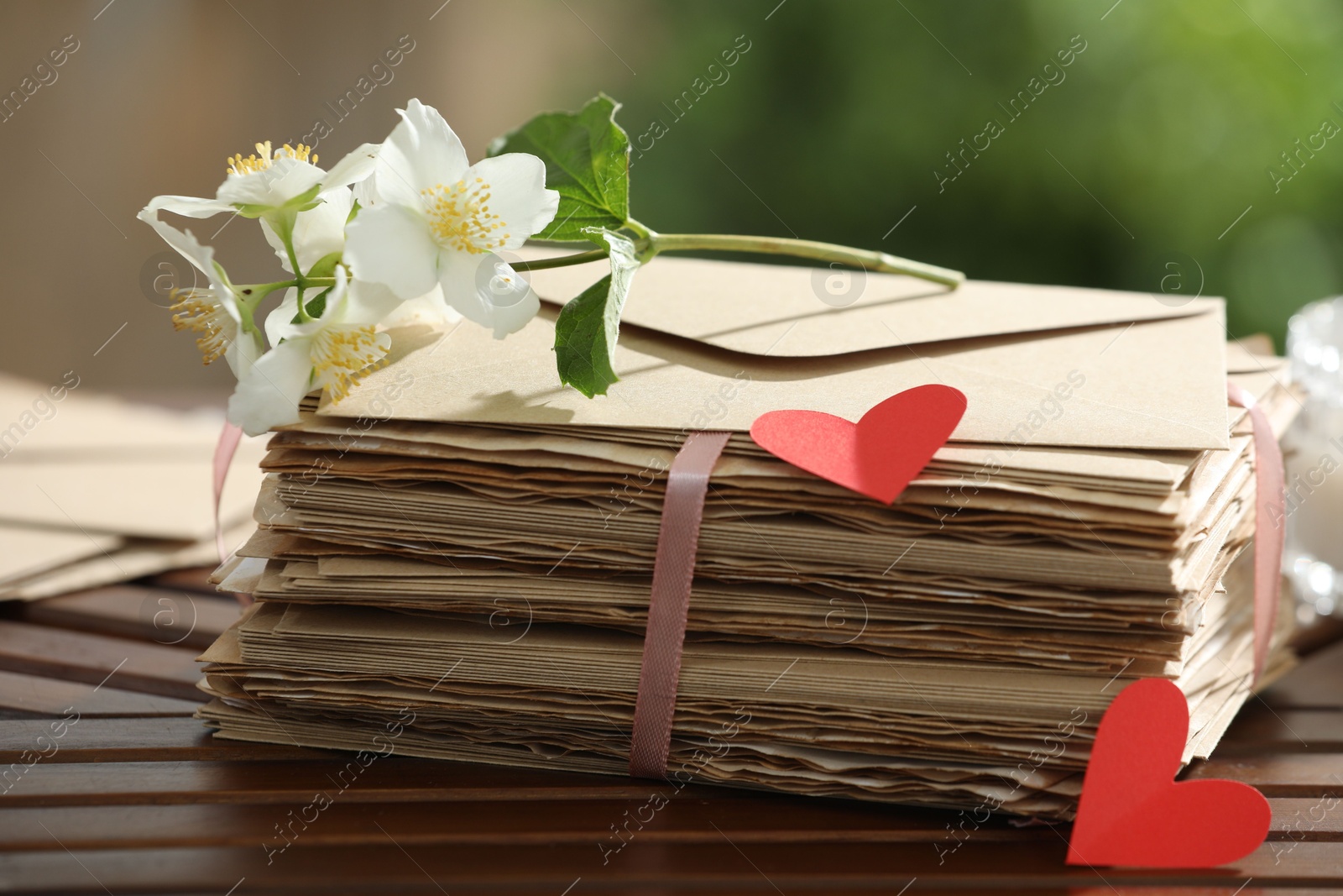 Stack of love letters, paper hearts and flowers on wooden table, closeup Photo of Stack of love letters, paper hearts and flowers on wooden table, closeup