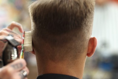 Photo of Professional barber making stylish haircut in barbershop, closeup
