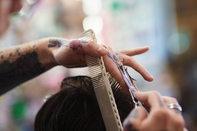 Photo of Professional barber cutting client's hair with scissors in barbershop, closeup