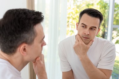 Photo of Handsome man after shaving near mirror at home