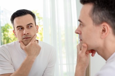 Photo of Handsome man after shaving near mirror at home