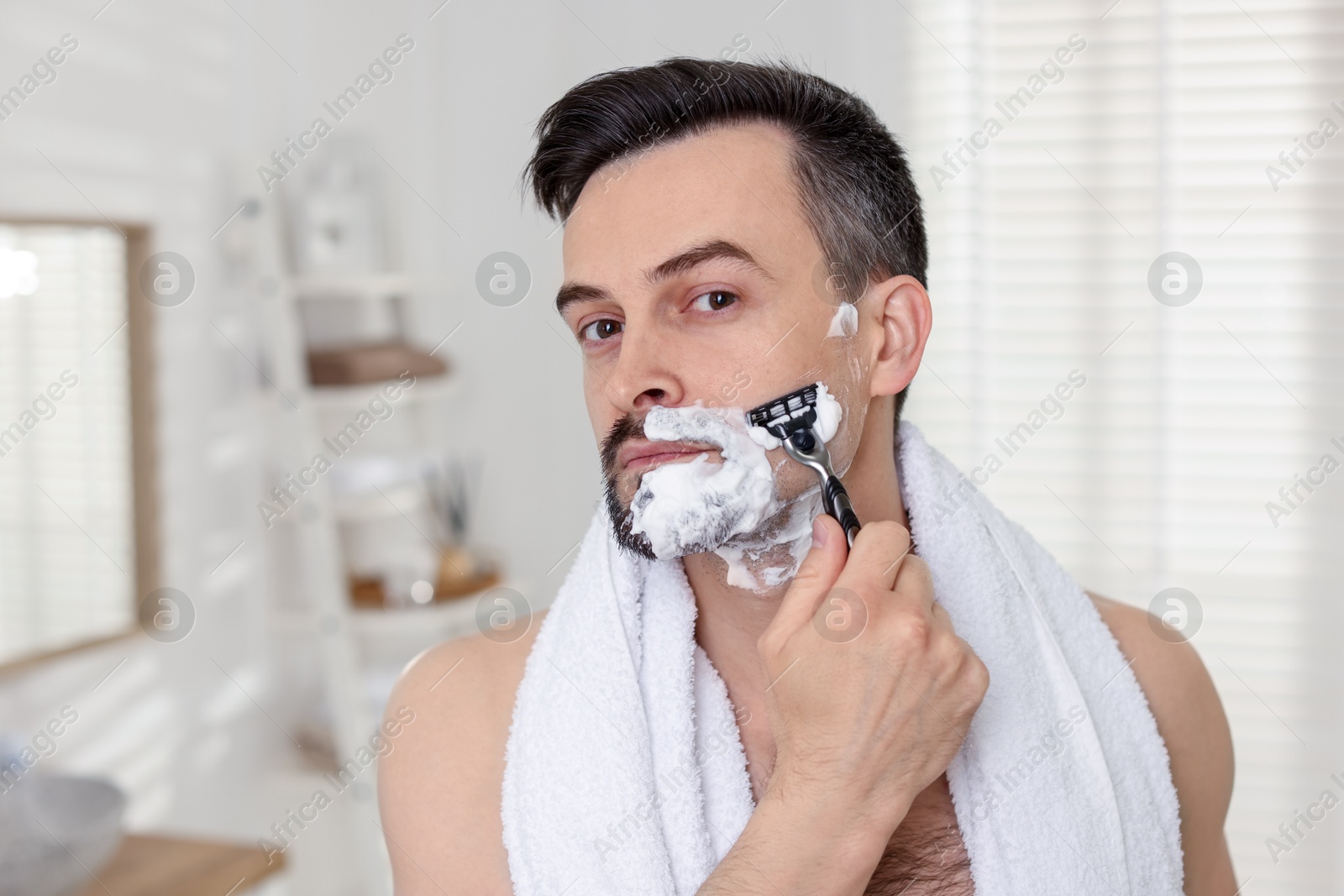 Handsome man shaving with razor at home Photo of Handsome man shaving with razor at home