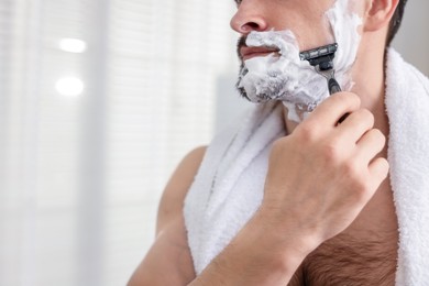 Photo of Man shaving with razor at home, closeup. Space for text