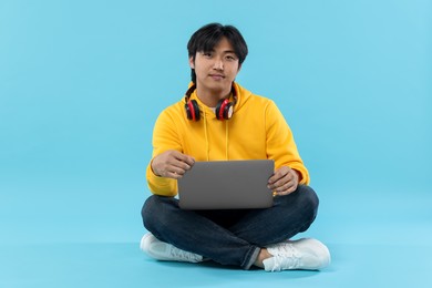 Photo of Student with headphones and laptop on light blue background