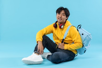 Photo of Student with headphones and backpack on light blue background