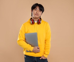 Photo of Student with headphones and laptop on beige background