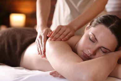 Photo of Woman receiving back massage with oil in spa salon