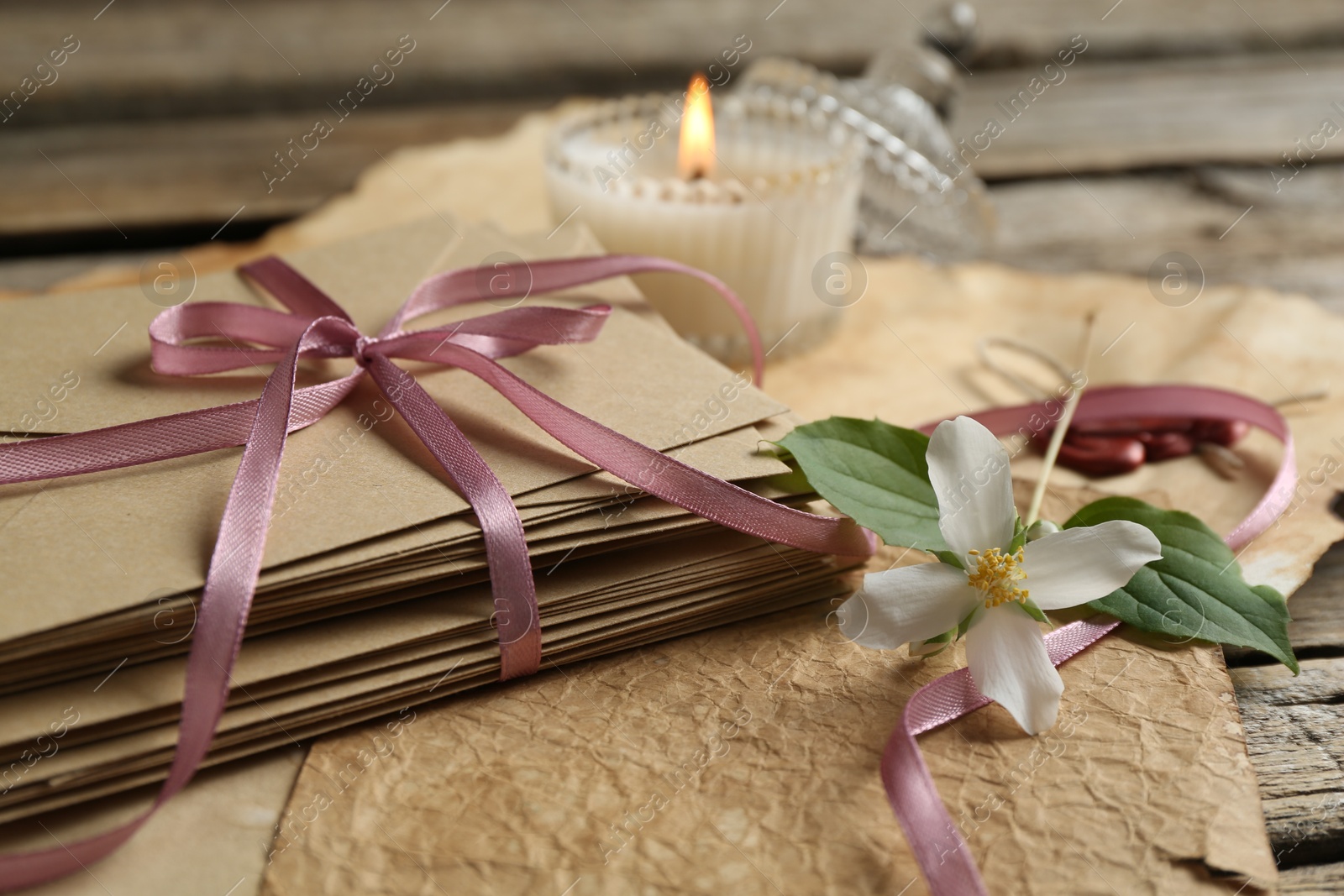 Stack of love letters, flower, candle and parchment sheets on wooden table, closeup Photo of Stack of love letters, flower, candle and parchment sheets on wooden table, closeup