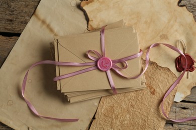 Photo of Stack of love letters and parchment sheets on wooden table, top view