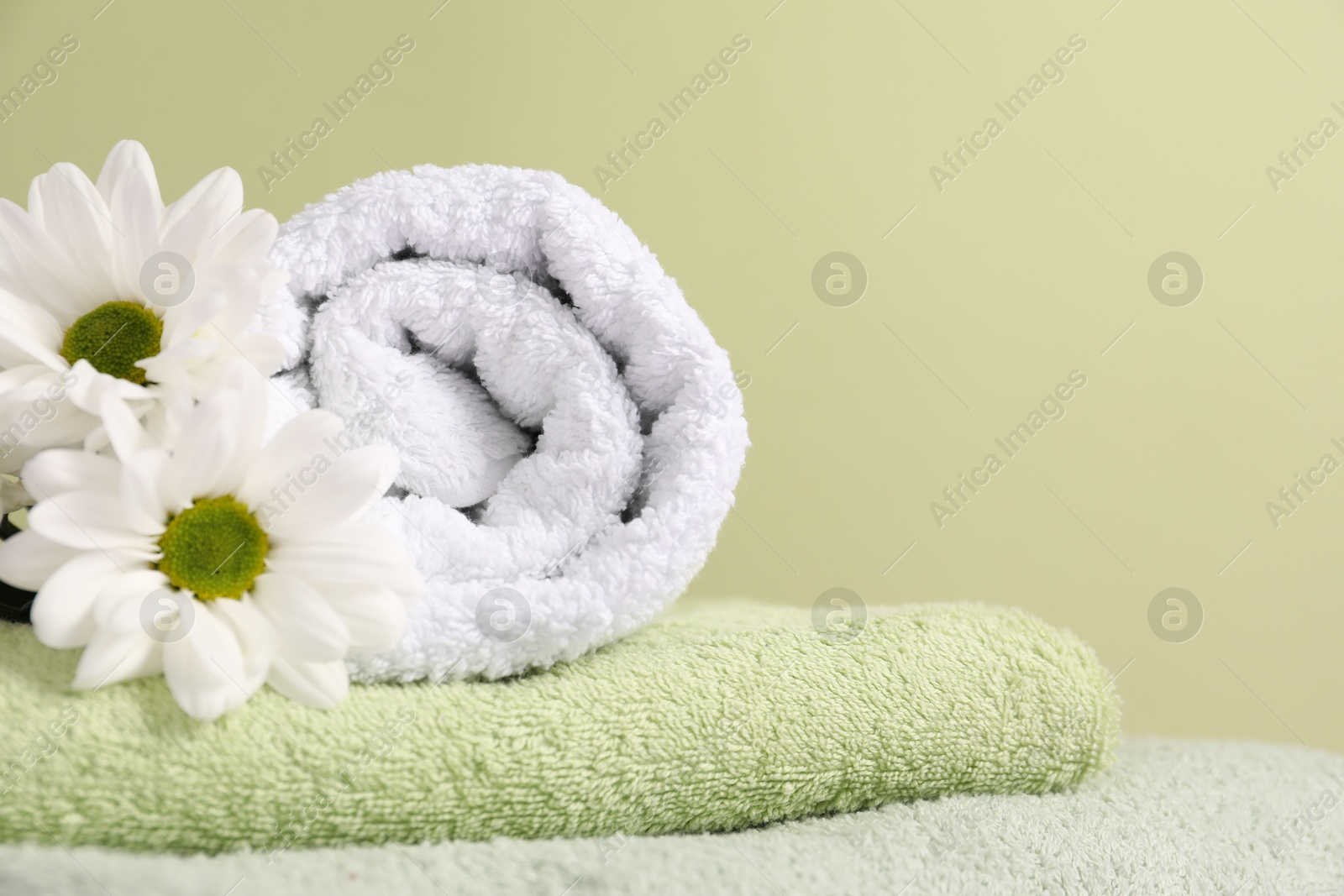Soft towels and chrysanthemum flowers on pale green background, closeup Photo of Soft towels and chrysanthemum flowers on pale green background, closeup