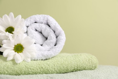 Photo of Soft towels and chrysanthemum flowers on pale green background, closeup