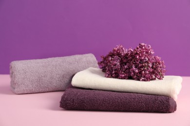 Photo of Soft towels and lilac flowers on color background
