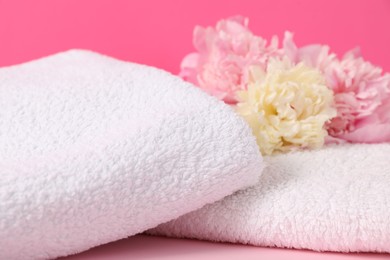 Photo of Soft towels and peony flowers on pink background, closeup