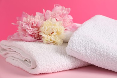 Photo of Soft towels and peony flowers on pink background, closeup