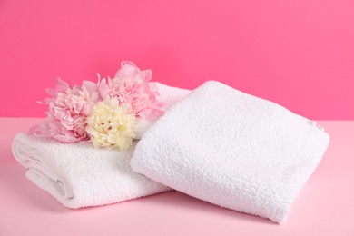 Photo of Soft towels and peony flowers on pink background