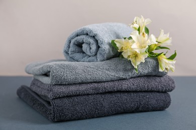 Photo of Soft towels and lilies on grey table against beige background, closeup