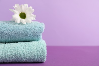 Photo of Soft towels and chrysanthemum flower on color background, closeup. Space for text