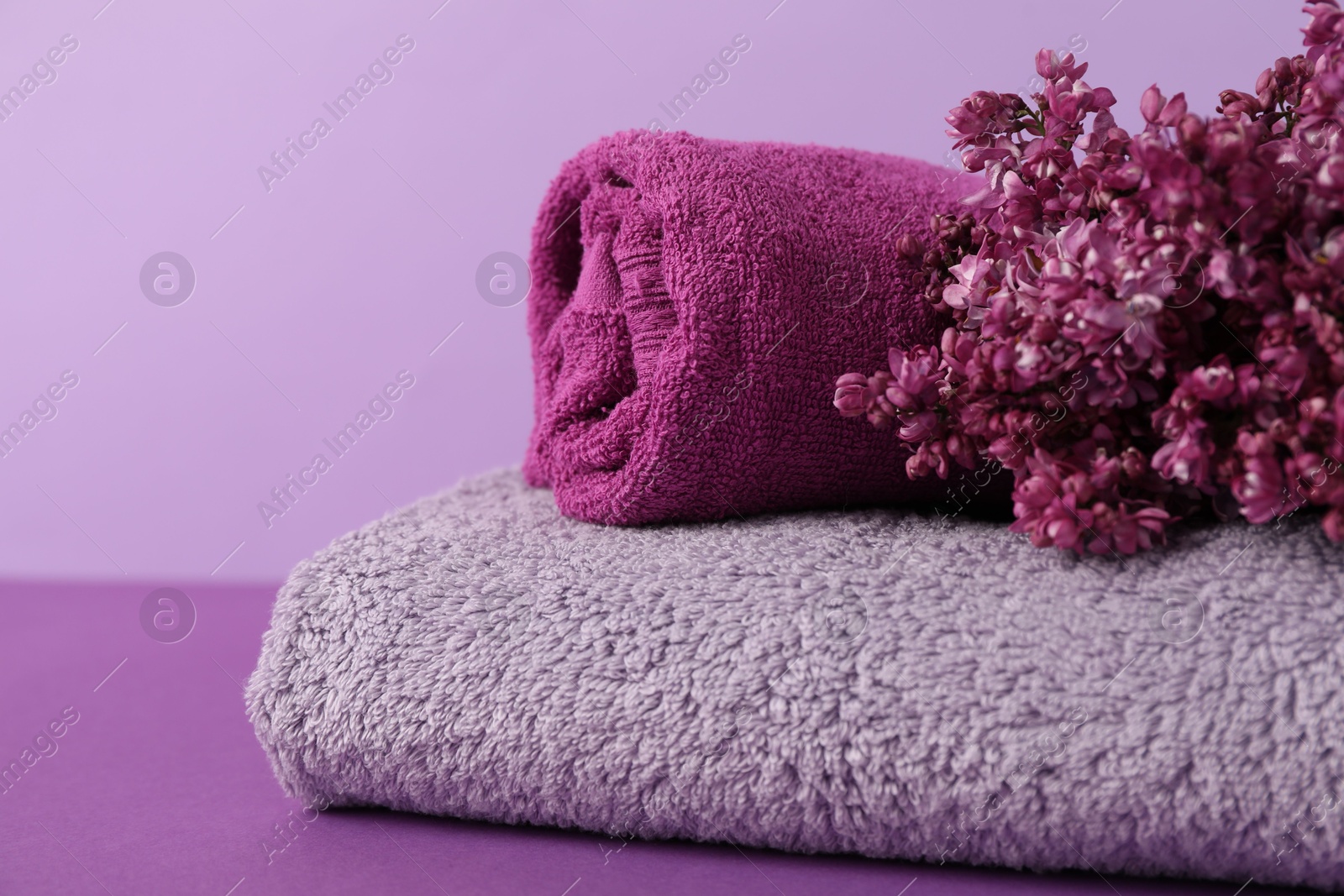 Soft towels and lilac flowers on color background, closeup Photo of Soft towels and lilac flowers on color background, closeup