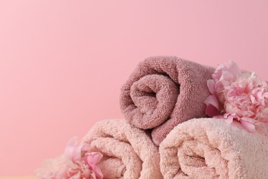 Photo of Soft towels and peony flowers on pink background, closeup. Space for text