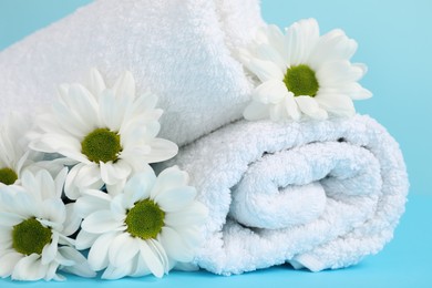 Photo of Soft towels and chrysanthemum flowers on light blue background, closeup
