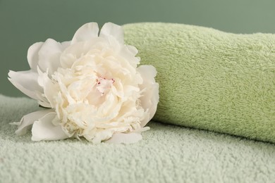 Photo of Soft towels and peony flower on green background, closeup