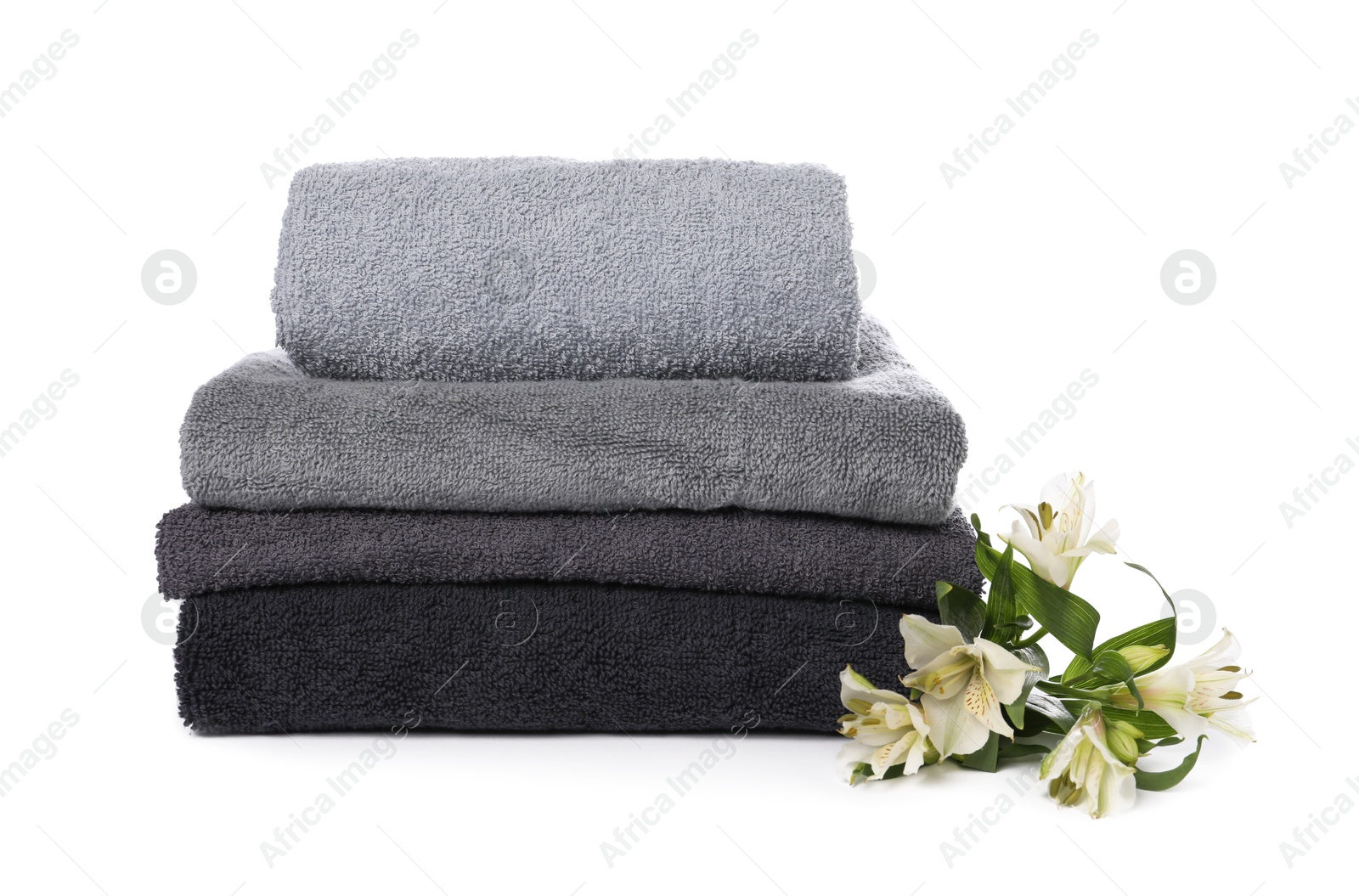 Stack of towels and beautiful flowers isolated on white Photo of Stack of towels and beautiful flowers isolated on white