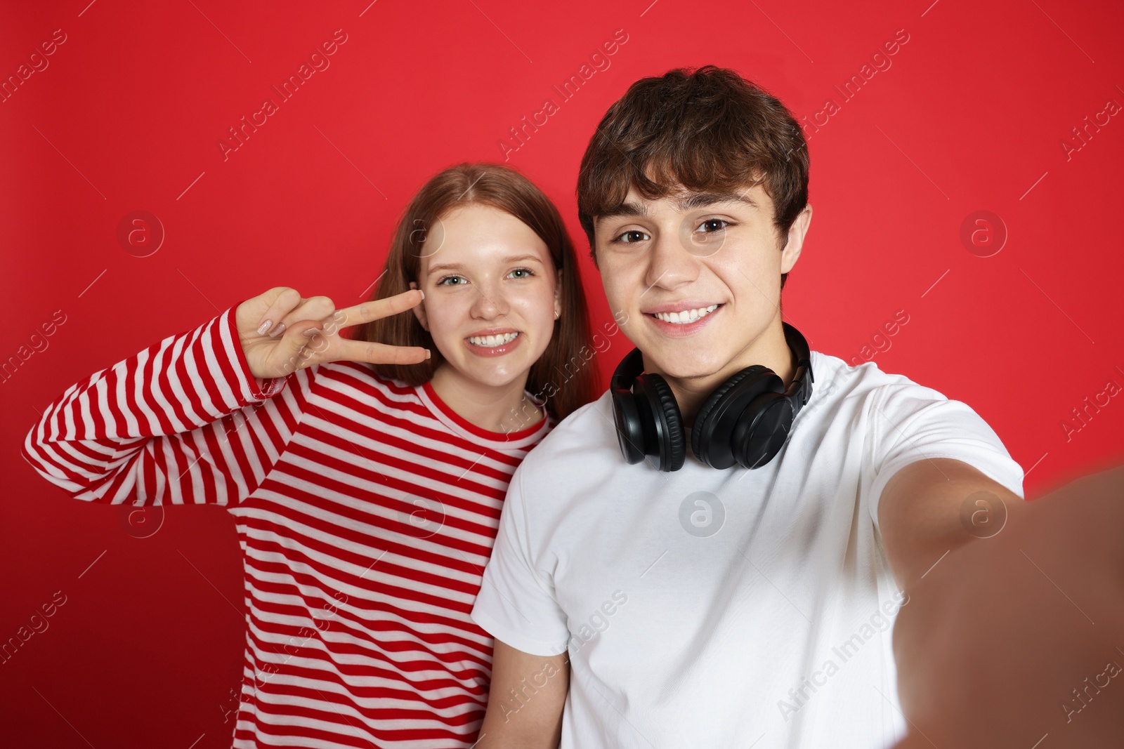 Teenage girl and boy taking selfie on red background Photo of Teenage girl and boy taking selfie on red background