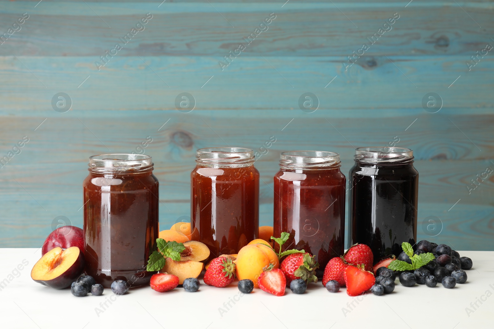 Different jams in jars and ingredients on white table. Space for text Photo of Different jams in jars and ingredients on white table. Space for text